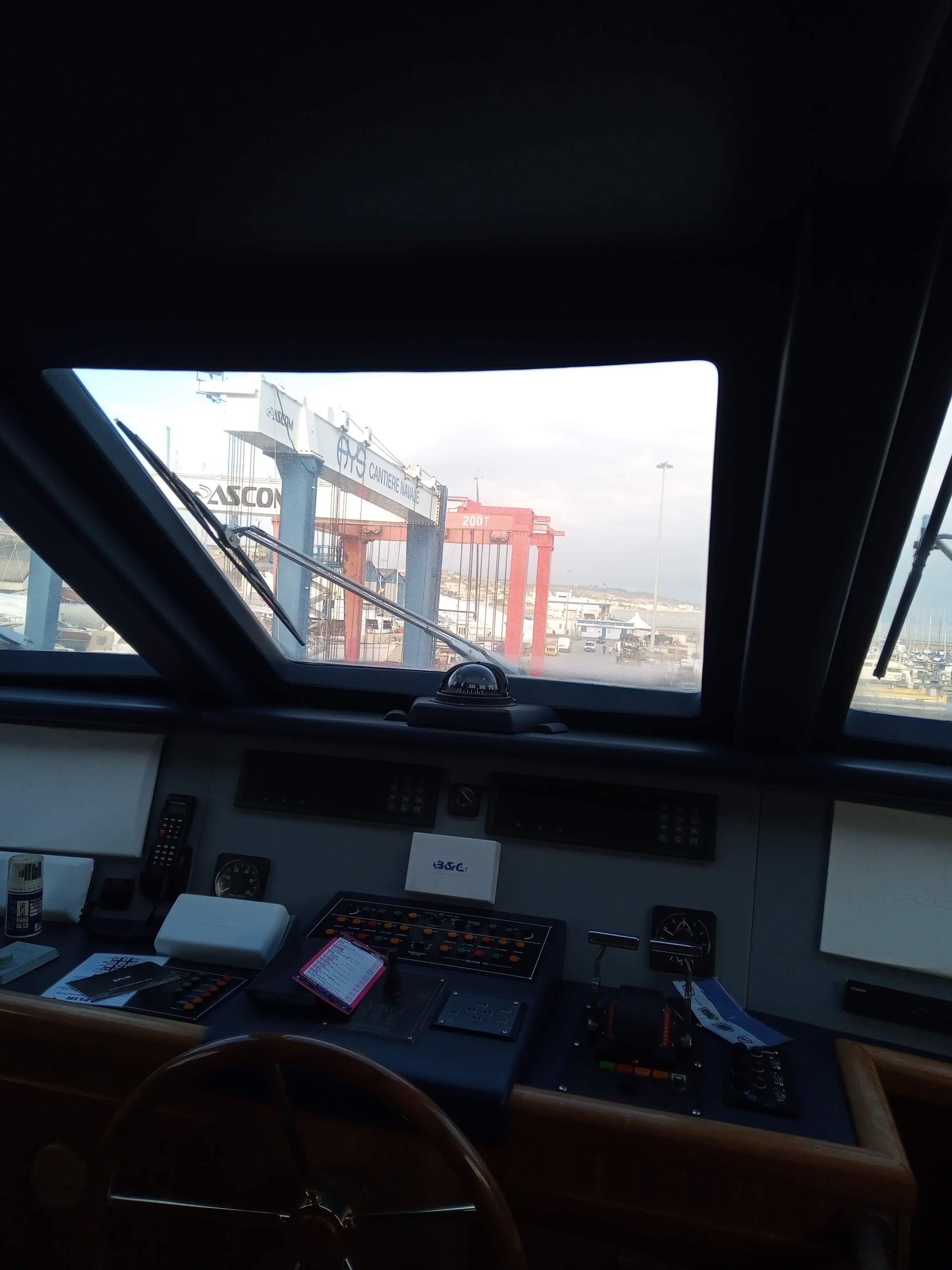 Plancia di un'imbarcazione con cantiere navale sullo sfondo